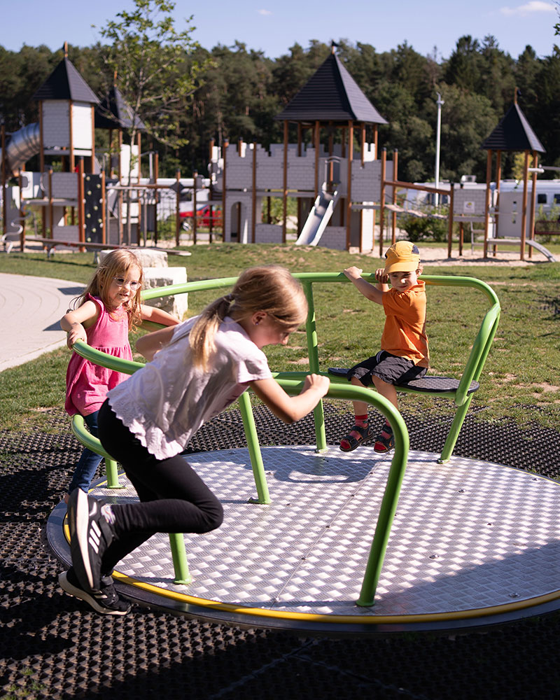 Die Kinder arbeiten zusammen, um ein Karussell zu fahren, einige ziehen, andere setzen sich hin und genießen die Fahrt.